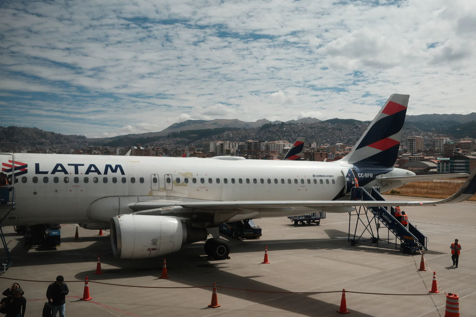 Ein Passagierflugzeug steht auf dem Flughafen von Cusco vor der dicht bebauten Berglandschaft.